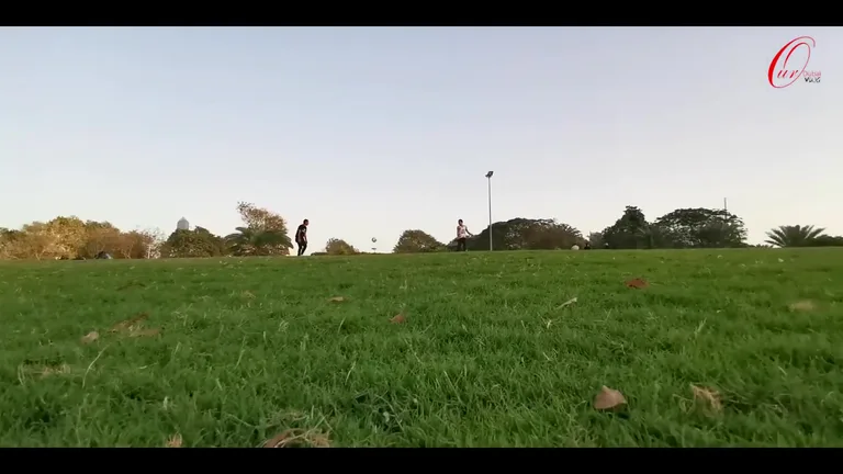 Архитектурное сооружение Dubai Frame на фоне ясного неба и зеленых лужаек парка Zabeel с отдыхающими людьми.