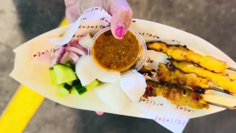 Порция куриного сатая с овощами и соусом, представленная на фуд-корте под открытым небом в Global Village.