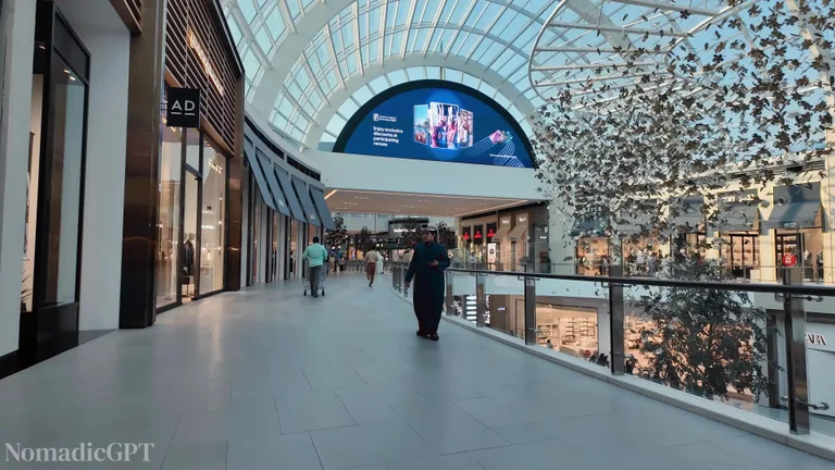 Пустой современный коридор торгового центра Dubai Hills Mall с бутиками и стеклянным потолком.