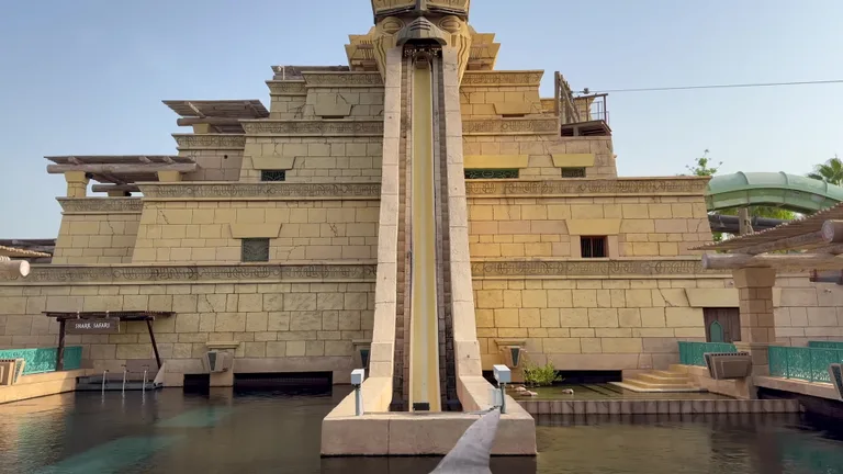 Горка Башня Нептуна в аквапарке Aquaventure с акулим плавником, виднеющимся в воде лагуны у ее основания.