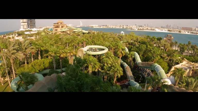 Панорамный вид сверху на водные горки аквапарка Aquaventure, проходящие через тропические деревья рядом с Персидским заливом.