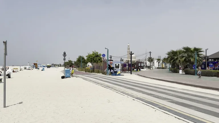 Отдыхающие и купающиеся люди на пляже Kite Beach с белым песком и бирюзовой водой.